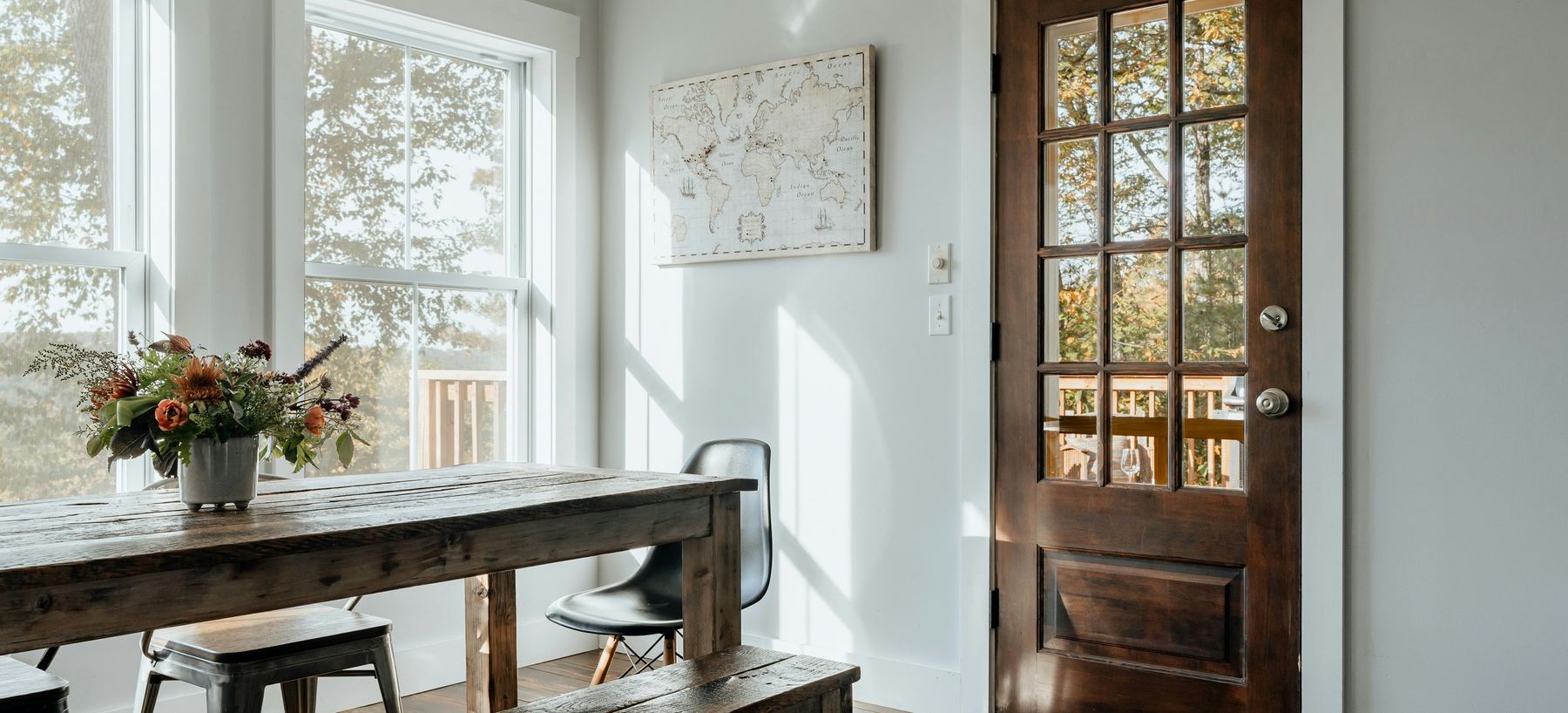 Dining room with a reclaimed wood table, autumn light and a world map on the wall