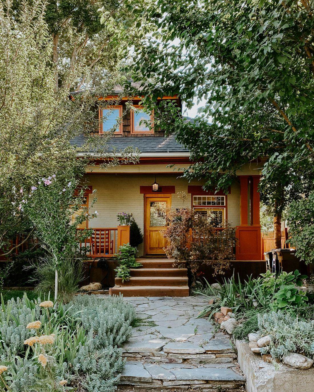 A craftsman bungalow with a stone path and mature garden