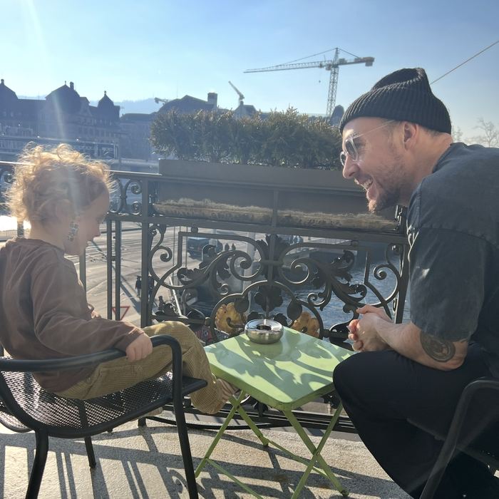 Mitch and his son at a cafe table overlooking the river in Zurich